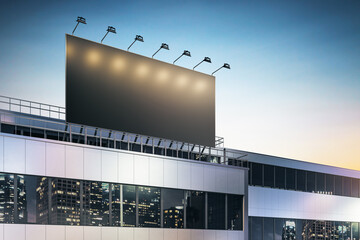 Black lighted billboard with copyspace on business center rooftop with spotlights and night city skyscrapers reflection in building windows. 3D rendering, mock up