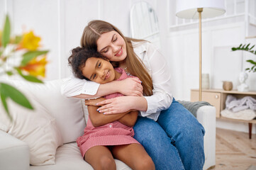 Mother hugs her little daughter in living room
