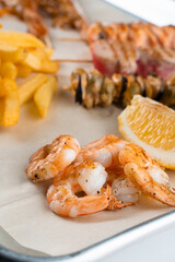 Set of seafood with grilled shrimps on metal plate with carrot, lettuce close-up.