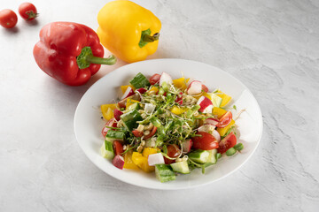 Wheat germ salad, tomatoes, peppers, radish, cucumber, olive oil. Vegetable salad on white plate on gray background.