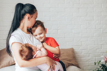 Young mother with two children and one kiss on the forehead