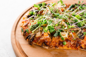Pinsa romana with salami, cheese, mushrooms, decorated with microgreens on wooden boardon white...