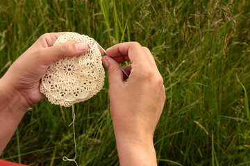 Woman's hands crocheting doily with hook, handmade process closeup