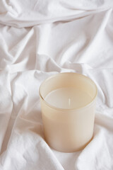 Fototapeta na wymiar aroma candle on white crumpled cotton fabric