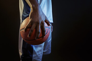 Basketball player holds ball, black background