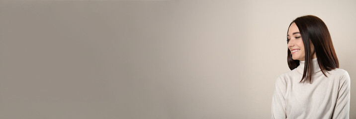 Portrait of pretty young woman with gorgeous chestnut hair and charming smile on light background, space for text. Horizontal banner design