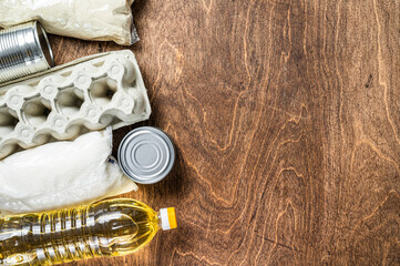 Food delivery Donation, quarantine help concept. Oil, canned food, pasta, bread, sugar, egg. Wooden background. Top view. Copy space