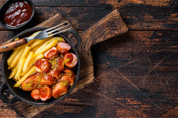Currywurst street food meal, Curry spice on wursts served French fries in a pan. Dark wooden...