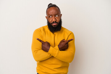 African american man with beard isolated on pink background points sideways, is trying to choose between two options.