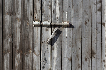 Wooden gate with a lock. Old bolt.