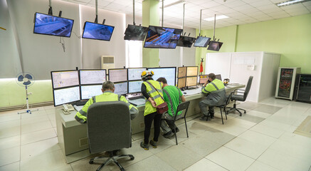 Workers in special clothes against the background of monitors, monitor technological processes. Technological works for the production of cement.