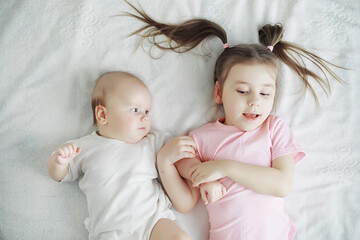 Children lie on the bed next to the newborn baby, little sister.