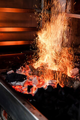 Grill barbecue with sparks and high fire with charcoal and firewood roasting. Getting ready for...