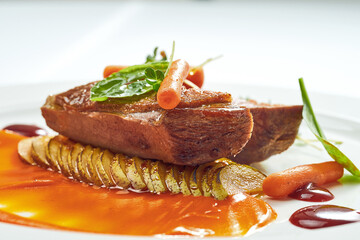 Appetizing confit duck breast with pear and yellow apple puree, berry sauce in a white plate. Isolated on grey background.