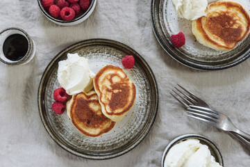 Healthy summer breakfast: Homemade fluffy pancakes with raspberry and whipped cream (chantilly) on greige linen tablecloth. Selective focus