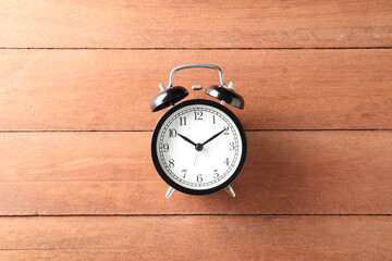 black alarm clock on wood background with copy space for text or image