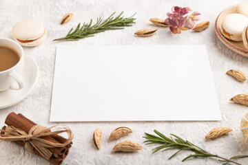 White paper sheet mockup with cup of coffee, almonds and macaroons on gray concrete background. business card, side view