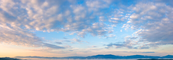 Fototapeta na wymiar fluffy clouds on the azure sky at sunrise. beautiful nature background. panoramic view in golden morning light