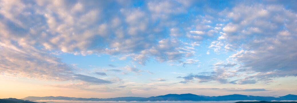 fluffy clouds on the azure sky at sunrise. beautiful nature background. panoramic view in golden morning light