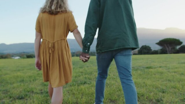 Mixed race couple walking romantically through park holding hands