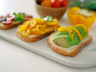 Vegan bruschetta. Delicious bruschetta with tomatoes, yellow peppers and avocado on a white plate. Appetizing Vegetable Snack Cheese Sandwiches