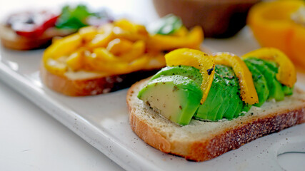 Vegan bruschetta. Delicious bruschetta with tomatoes, yellow peppers and avocado on a white plate. Appetizing Vegetable Snack Cheese Sandwiches