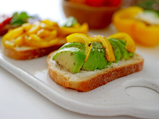 Vegan bruschetta. Delicious bruschetta with tomatoes, yellow peppers and avocado on a white plate. Appetizing Vegetable Snack Cheese Sandwiches