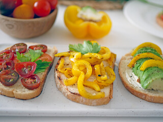 Vegan bruschetta. Delicious bruschetta with tomatoes, yellow peppers and avocado on a white plate. Appetizing Vegetable Snack Cheese Sandwiches