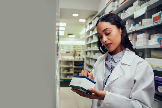 Woman Checking Medicine Box Reading Expiry Date And Instructions Standing In Aisle Of Chemist