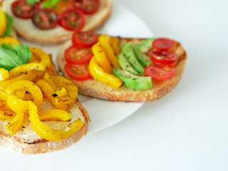 Vegan bruschetta. Delicious bruschetta with tomatoes, yellow peppers and avocado on a white plate. Appetizing Vegetable Snack Cheese Sandwiches