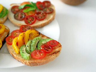 Vegan bruschetta. Delicious bruschetta with tomatoes, yellow peppers and avocado on a white plate. Appetizing Vegetable Snack Cheese Sandwiches