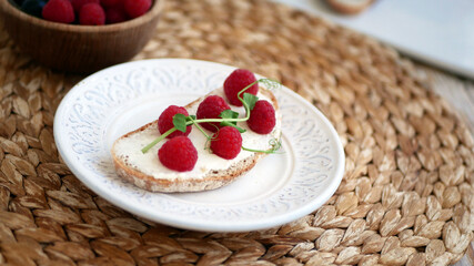 Sweet bruschetta with cream cheese and fresh berries. Homemade healthy breakfast with bread, cheese, blueberries and raspberries. Three delicious sandwiches on a plate