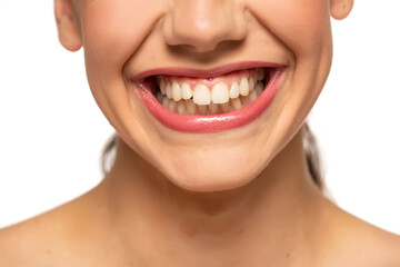 Fototapeta premium Close up of a young beautiful woman with a wide smile and healthy teeth on a white background