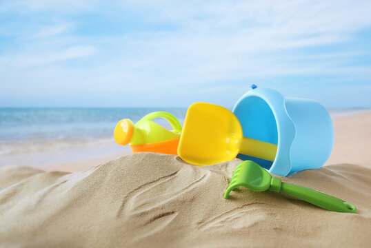 Plastic toy set with shovel on sandy beach near sea
