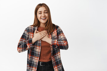 Thank you. Delighted young woman hold hands on heart chest, gazing touched and flattered,...