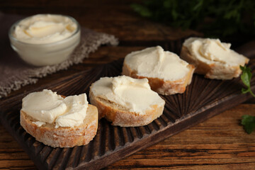 Obraz na płótnie Canvas Bread with cream cheese on wooden board, closeup