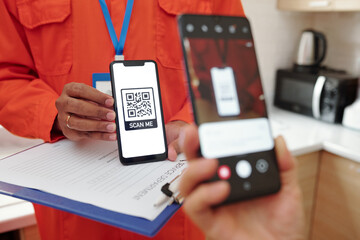 Close-up of unrecognizable client using smartphone camera while scanning QR code for payment of repair service