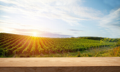 Brown wood table in autumn vineyard scenery against sunset sky with blank copy space on table for...