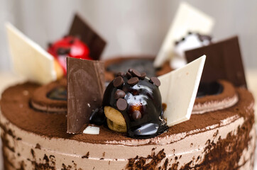 Decorating a chocolate cake close-up, with a ball poured with chocolate with slices of black and white chocolate