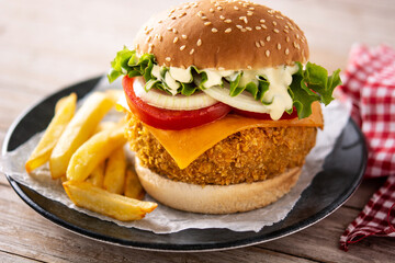 Crispy chicken burger with cheese on wooden table