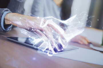 Double exposure of handshake hologram and man and woman working together holding and using a mobile device.