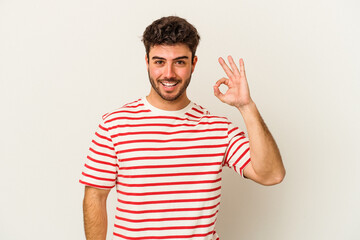Naklejka premium Young caucasian man isolated on white background cheerful and confident showing ok gesture.