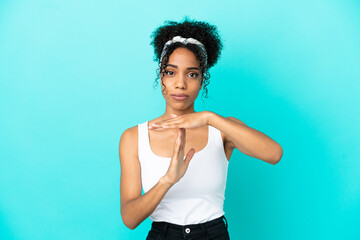 Young latin woman isolated on blue background making time out gesture