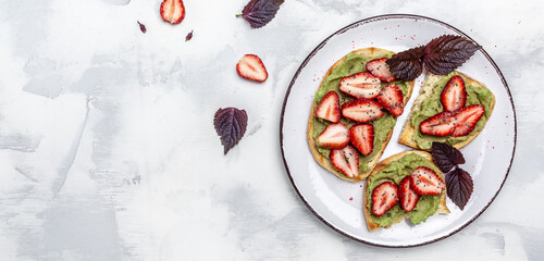 breakfast toast with guacamole, strawberries and chia seeds. Healthy summer snack. Avocado with strawberries. Keto diet toast. Vegan healthy food concept. Long banner format. top view