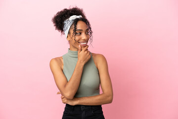 Young latin woman isolated on pink background looking to the side and smiling