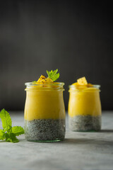 Chia mango pudding in glass jar. Homemade healthy desssert, dark background