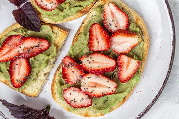 toast with shaped avocado,fresh strawberries and chia seeds on plate. vegan healthy food concept. Top view Food recipe background. Close up
