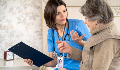 A young nurse takes care of an elderly 80-year-old woman at home, explains the methods of...