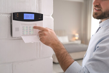 Man entering code on security alarm system at home, closeup - obrazy, fototapety, plakaty