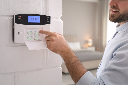 Man entering code on security alarm system at home, closeup